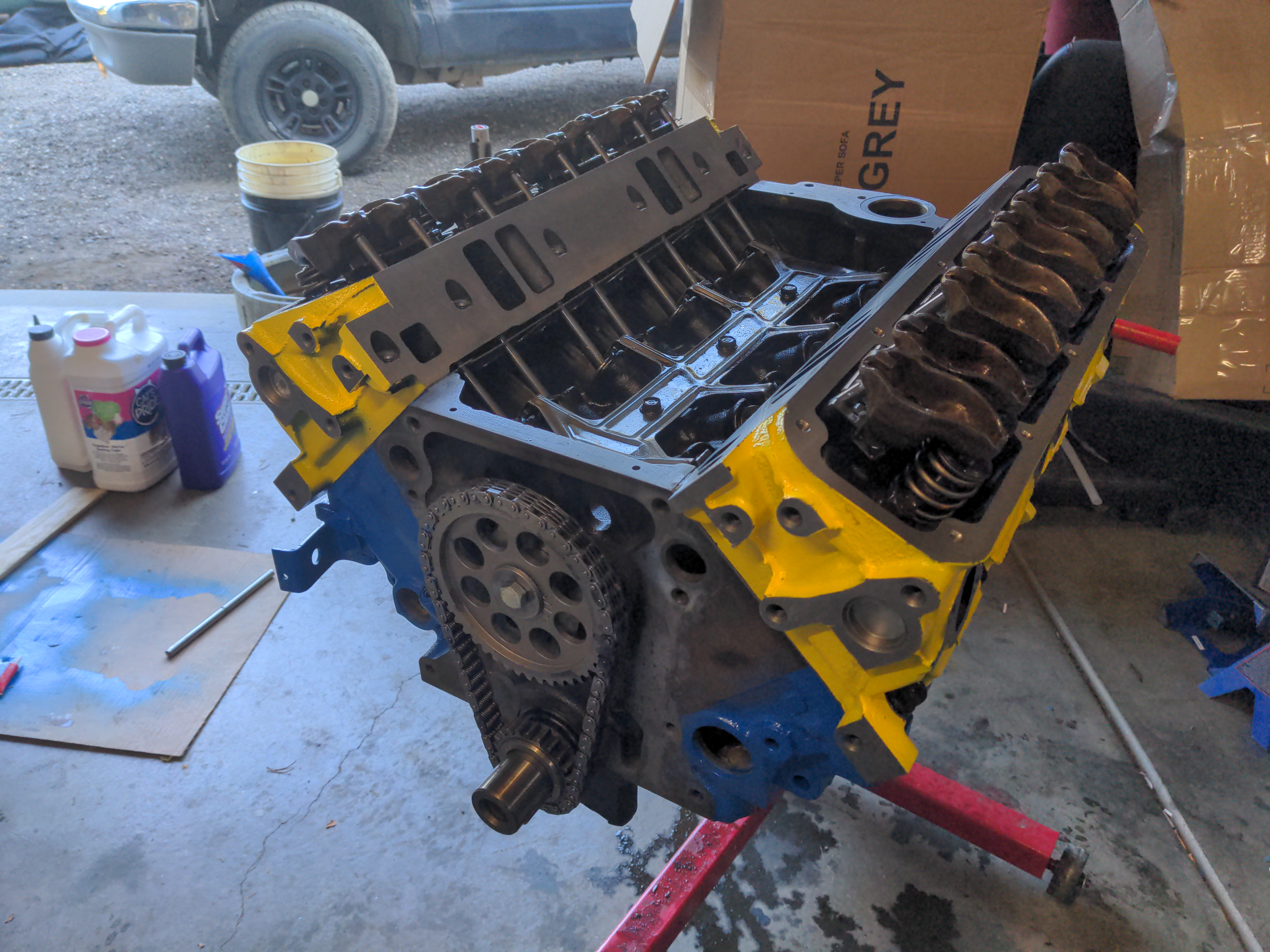 The project V8, with cylinder heads installed. These have been painted bright yellow, and they contrast the blue of the engine block sharply. This is starting to really look like an engine, rather than a pile of scrap parts.