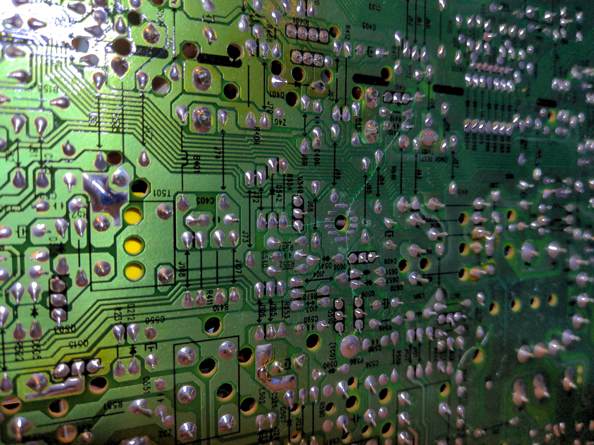 Closeup of a CRT control board, with damage visible around a mounting hole. The board is cracked in three directions radiating out from this mounting hole, with cracks through numerous traces.